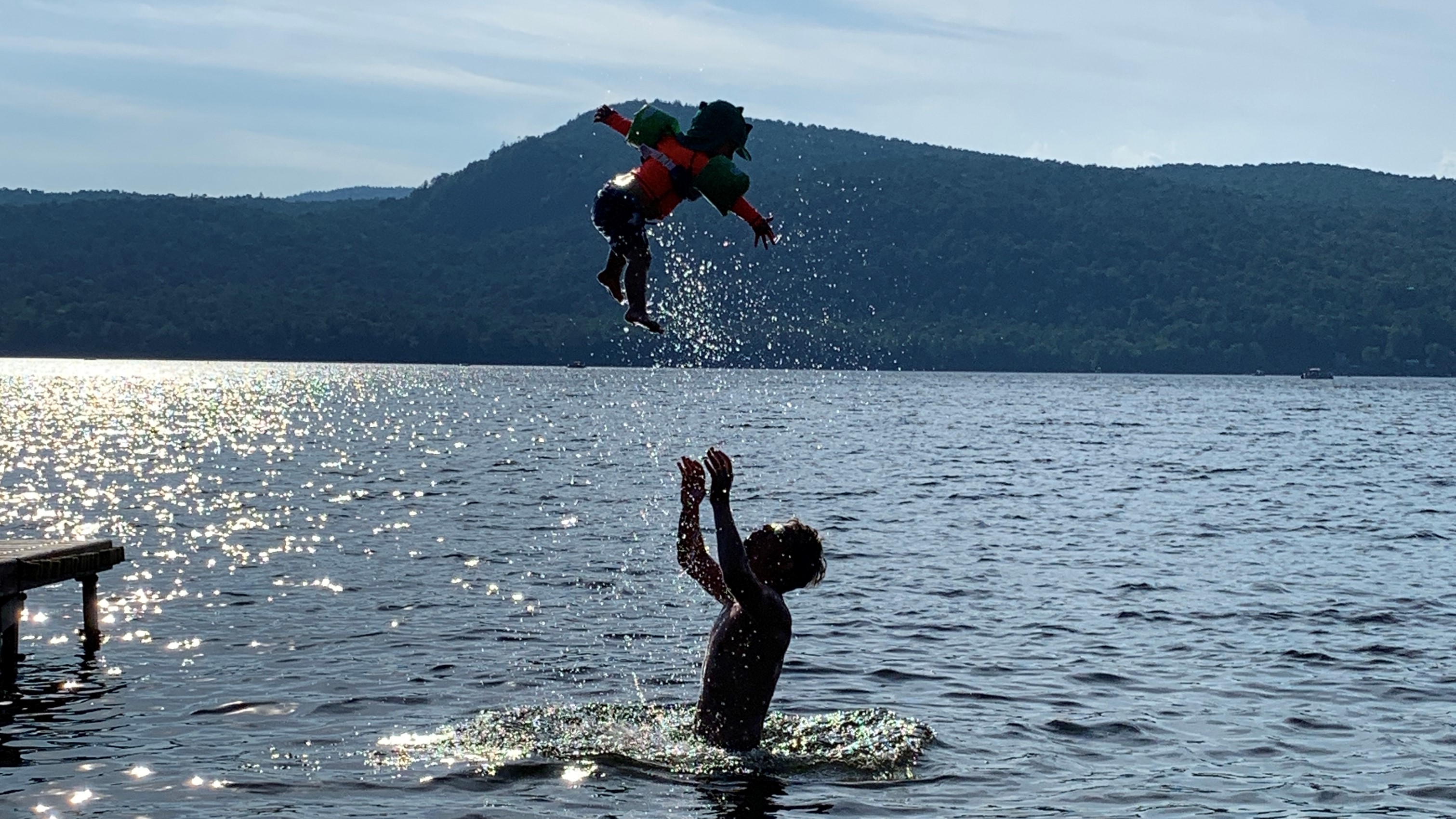 Man throwing kid into air while swimming in lake