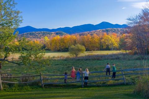 Kids stand on a fence looking at the McIntyre Range of the Adirondack High Peaks.