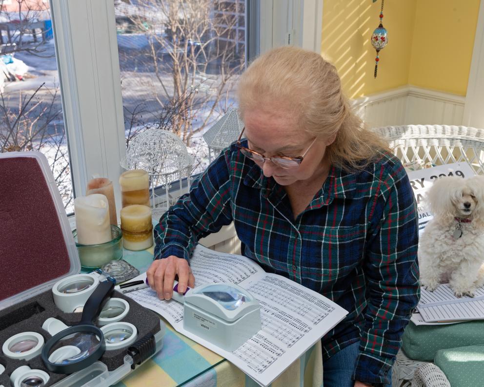 A woman uses a magnifying device to read.