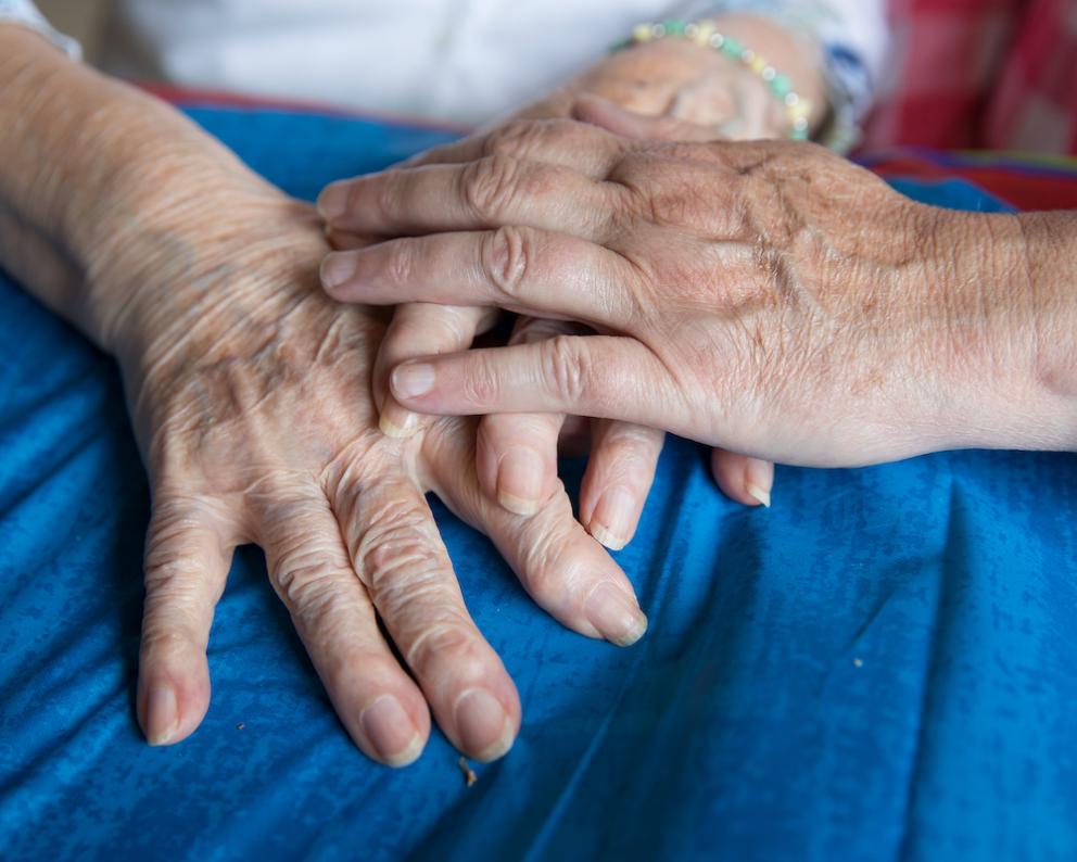 Young person's hand holding eldery person's hands