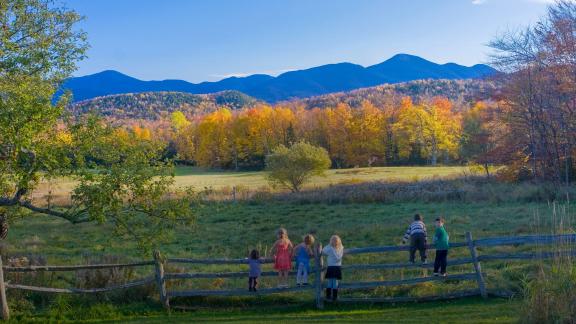 Kids stand on a fence looking at the McIntyre Range of the Adirondack High Peaks.