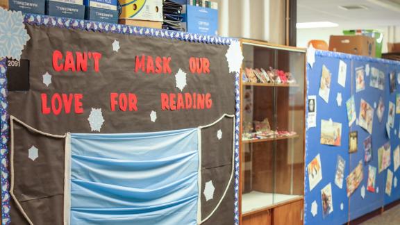 A sign with a giant mask at Ticonderoga Central School that reads "Can't mask our love for reading"